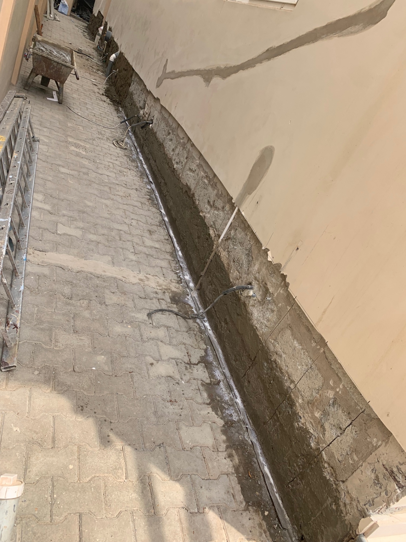 Perimeter wall base waterproofing and damp-proofing on paved walkway